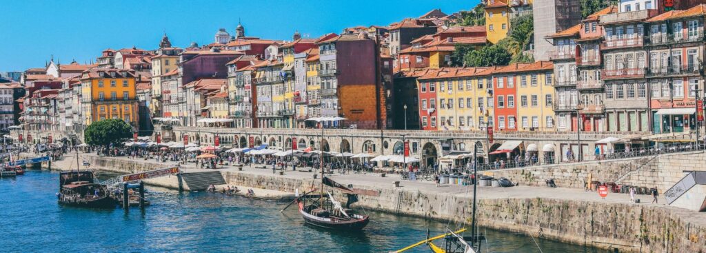 small boats in the river along a row of colorful buildings in porto, portugal