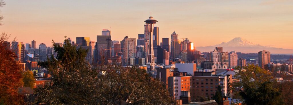 seattle skyline with the sun setting creating a pink and orange sky