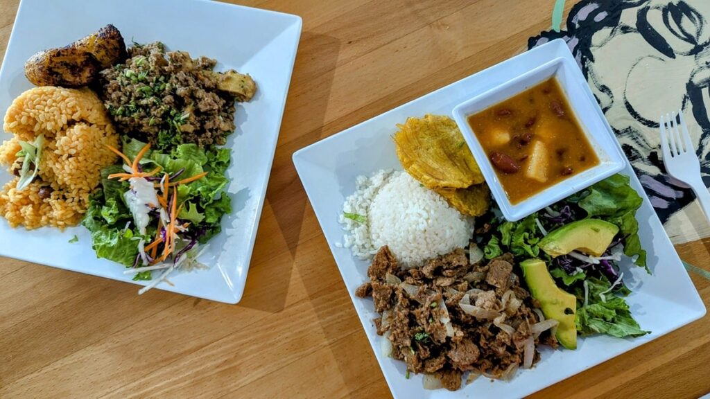 two plates with veganized puerto rican classics like rice with peas and impossible meat and rice with impossible steak and tostones at 100% HP in san juan