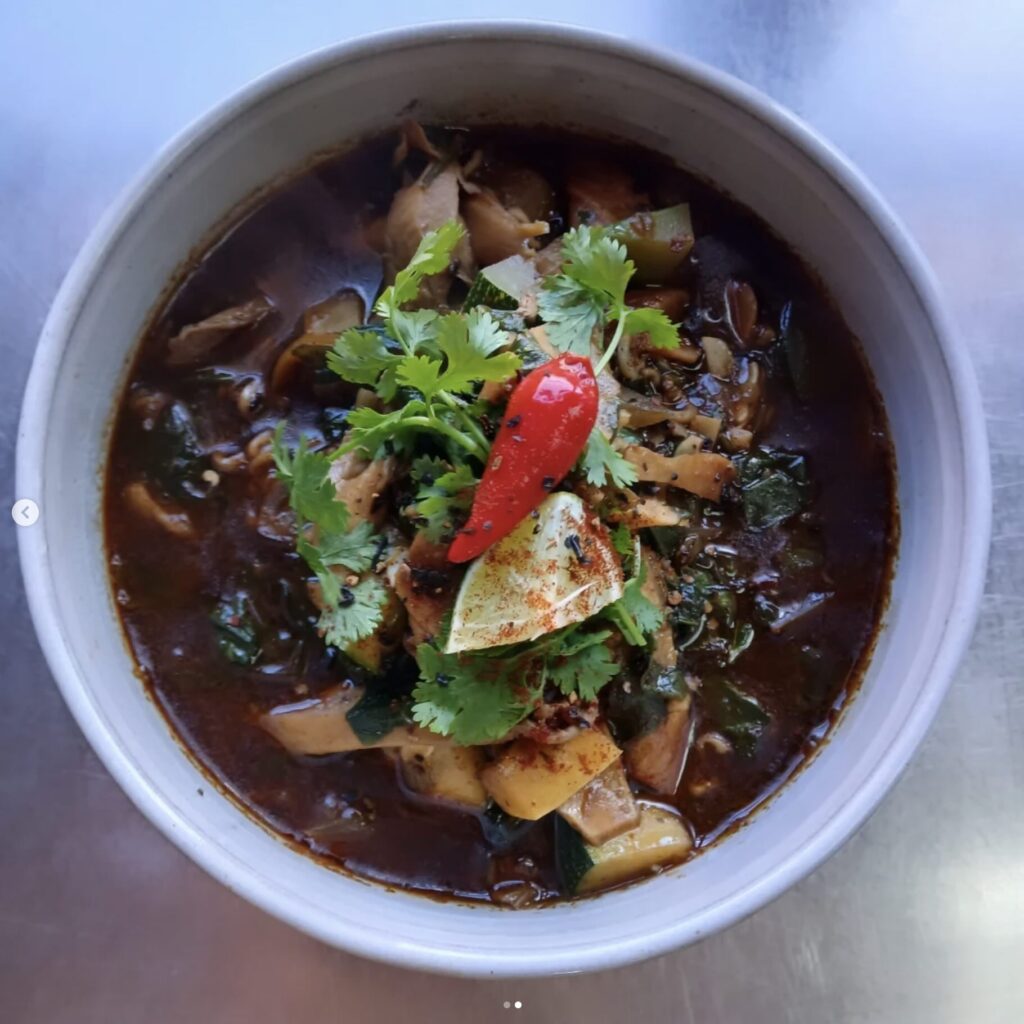 Chipotle & mole ramen in topped with red bell pepper in white bowl.