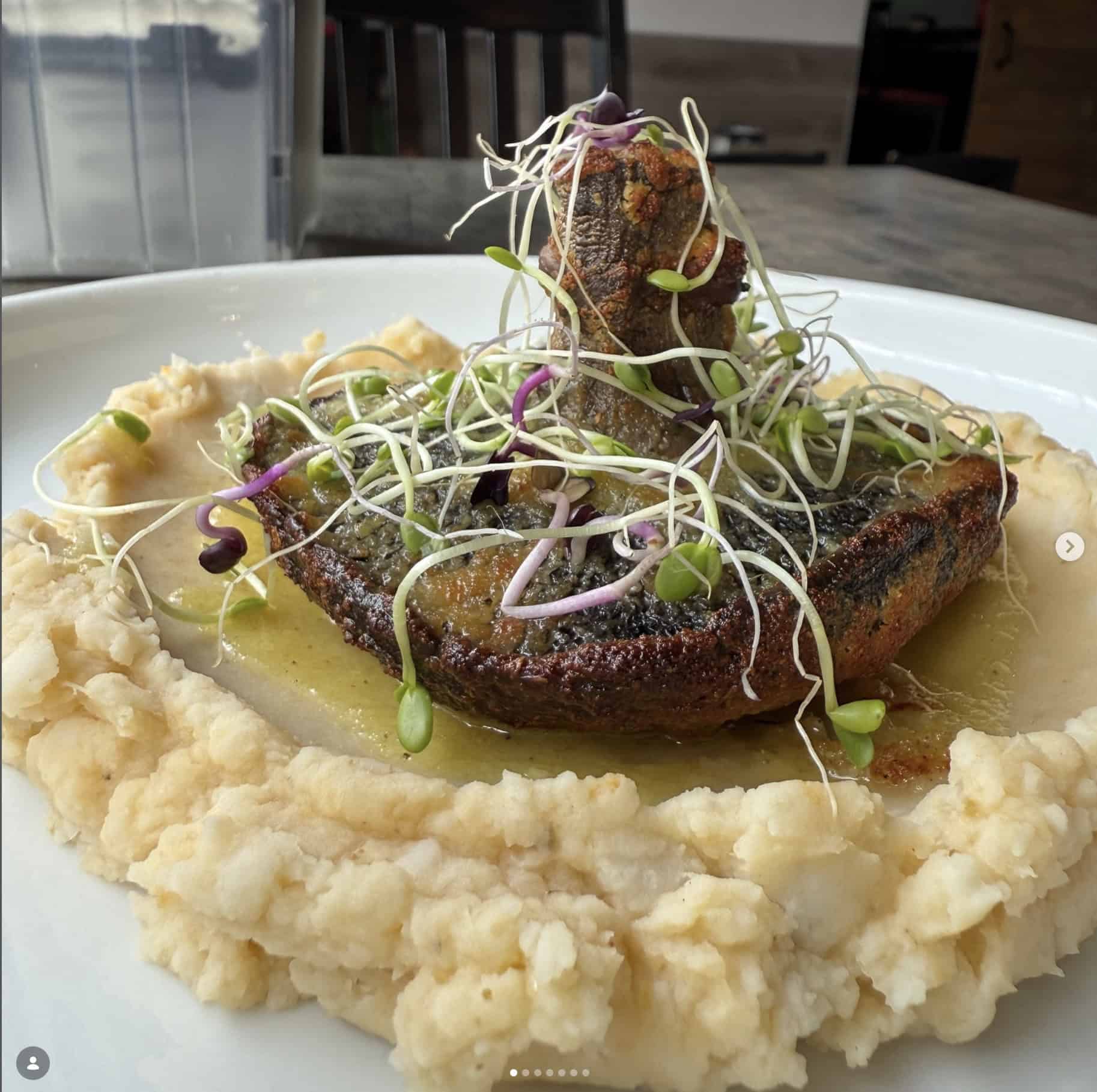 Roasted mushroom over a bed of mashed potatoes in white dish.