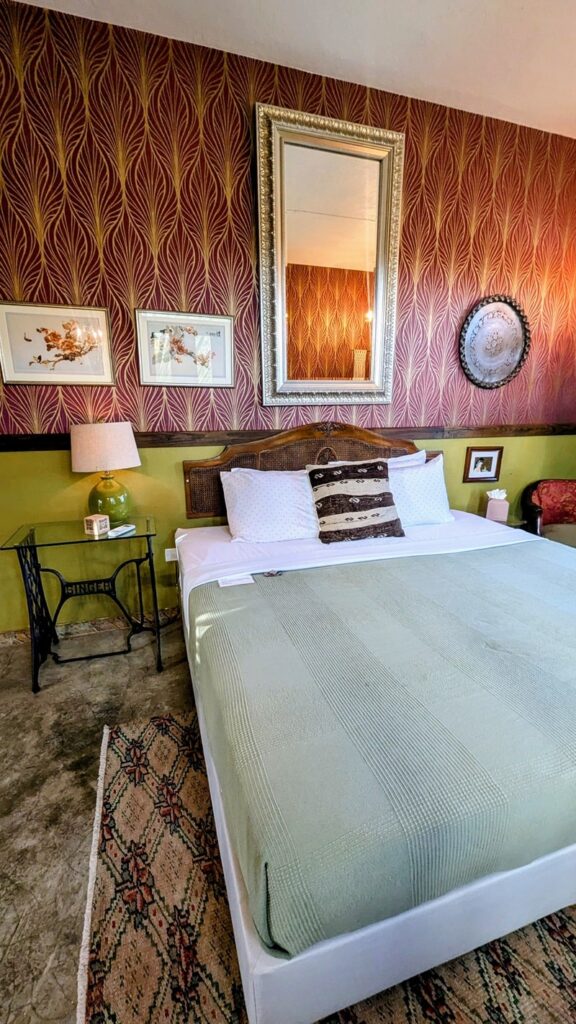 eccentric guestroom with red and gold wallpaper, a queen size bed and antique wall decor at dreamcatcher in san juan puerto rico