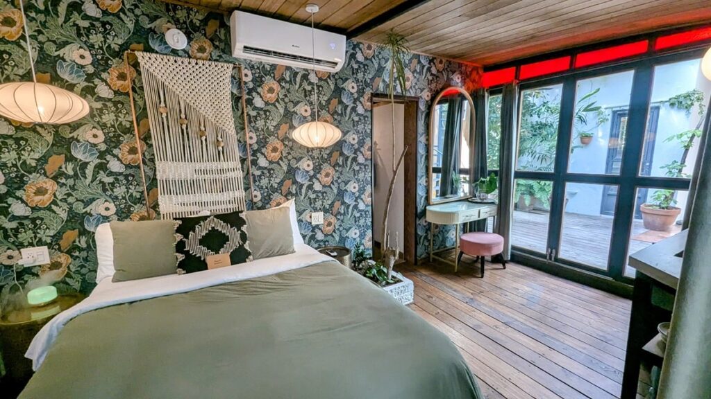 beautiful glasshouse suite with green floral wall paper, a queen sized bed and large windows at la botanica in san juan puerto rico