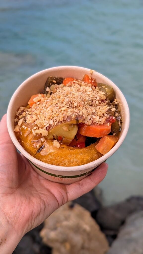 a medium sized bowl with vegan mofongo held over blue water in puerto rico