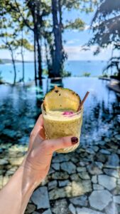 a small drink with a slice of pineapple on top held above a pool at arena beach resort in manuel antonio