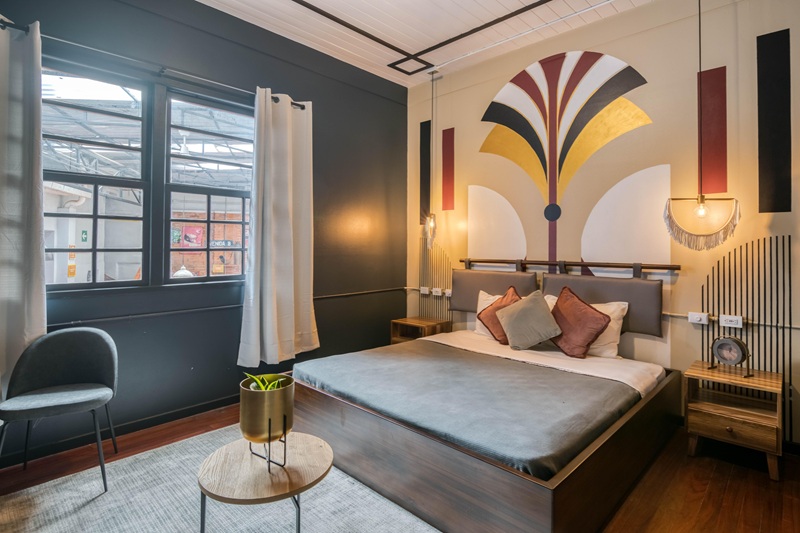 modern guestroom with a single bed in front of a colorful mural at selina san jose