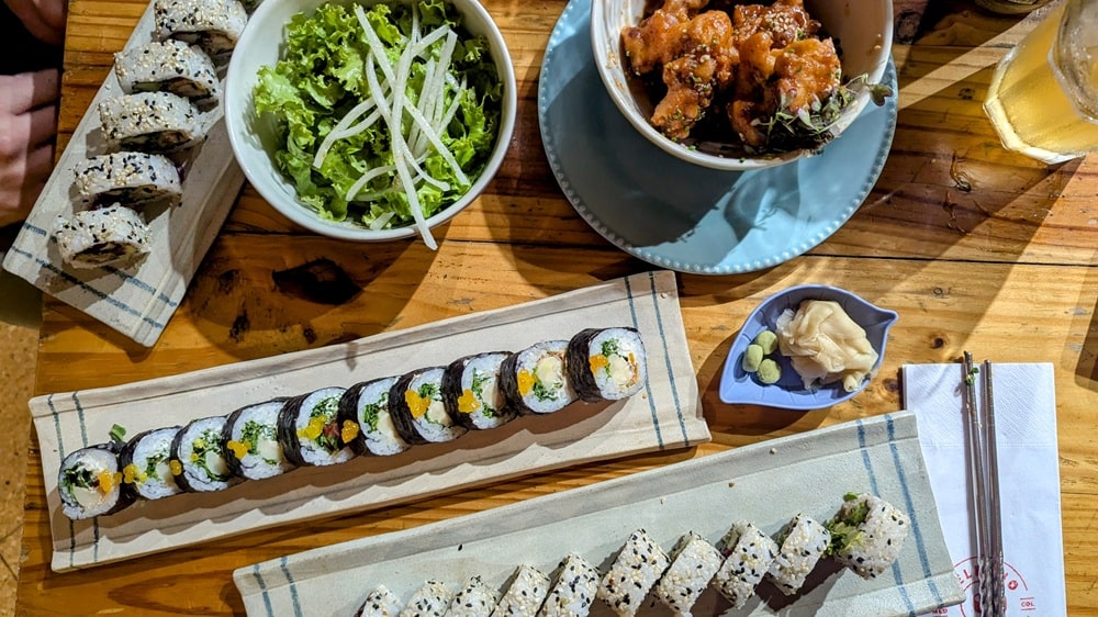overhead shot of three different vegan sushi rolls with fried cauliflower and salad at helecho sushi in medellin