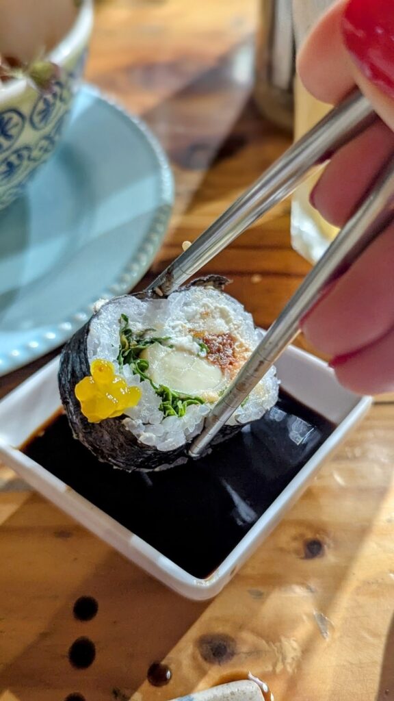a single vegan sushi roll being dipped into soy sauce at helecho sushi in medellin