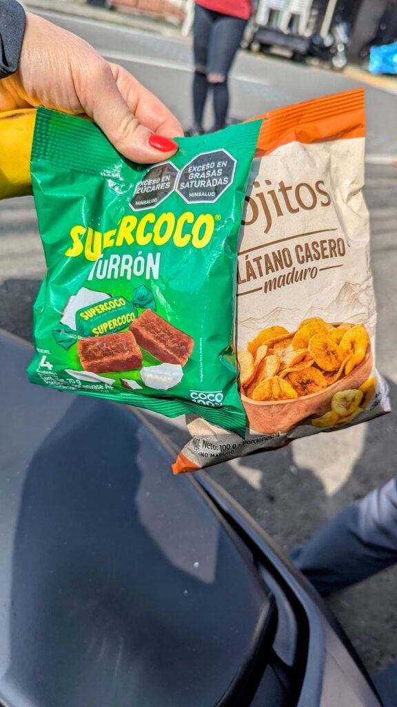 a bag of coconut candy and sweet plantain chips in front of a supermarket in colombia