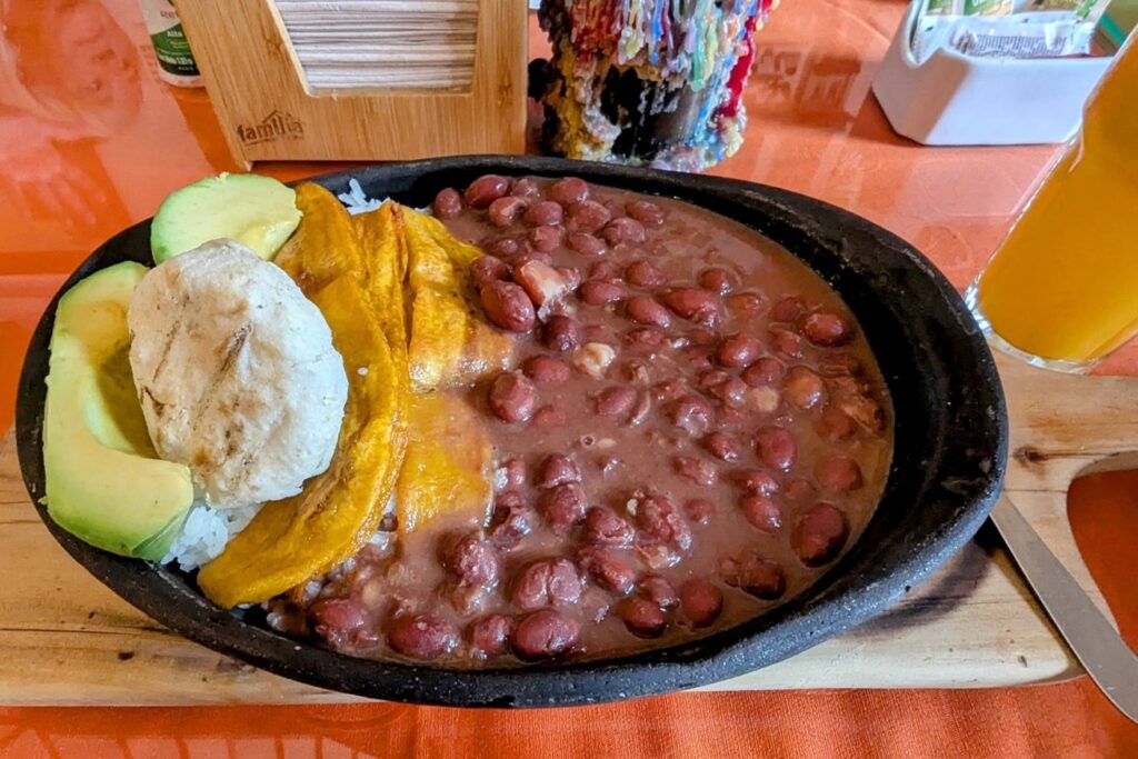 large black skillet filled with giant red beans with an arepa, plantains and avocado in salento, colombia