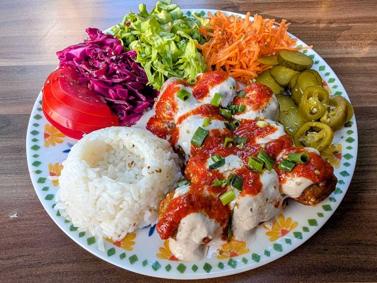 vegan turkish meatballs covered in a cream sauce with salad and pickled veggies at Veganarsist in istanbul