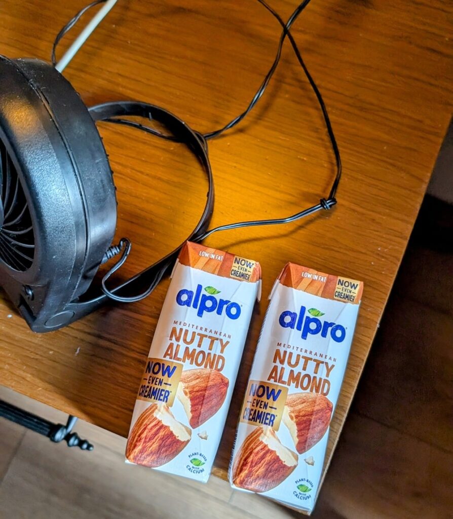 two small cartons of almond milk on a bed side table