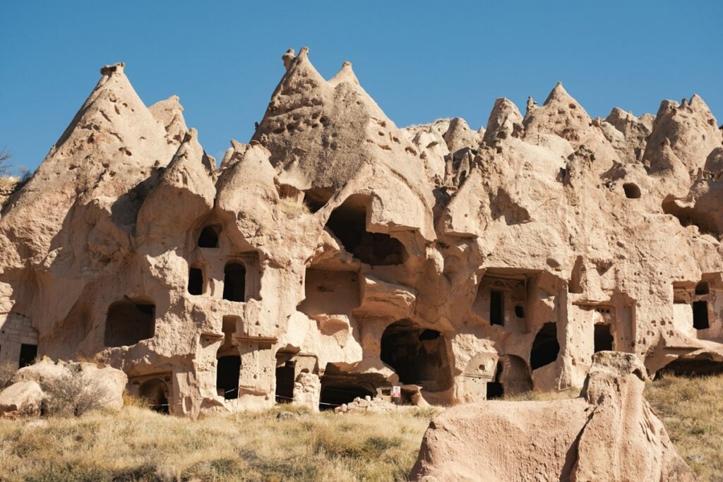 the outside of a cave house built into a mountain  in a valley in cappadocia