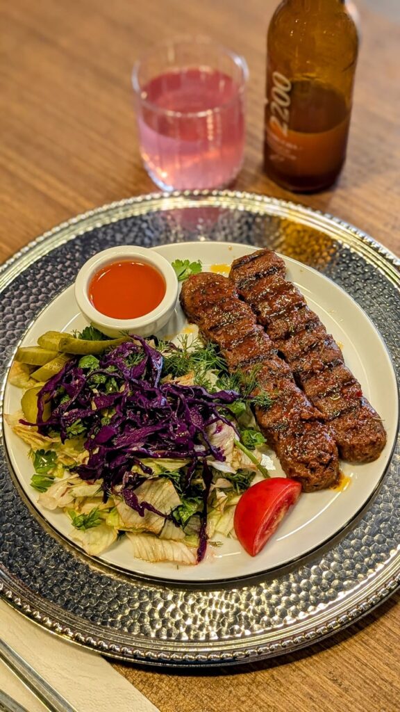two vegan kebabs with salad next to a pink glass of kombucha at wegain vegan restaurant in istanbul