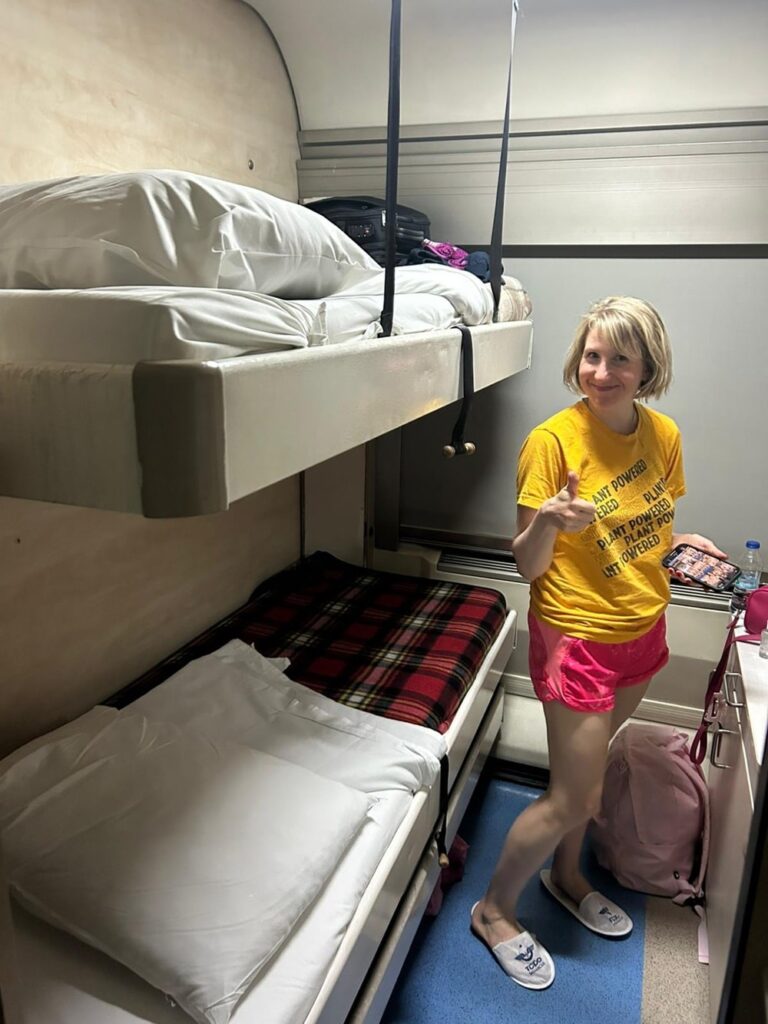 rebecca gade sawicki standing next to two bunk beds on an overnight train from izmir to konya in tukey