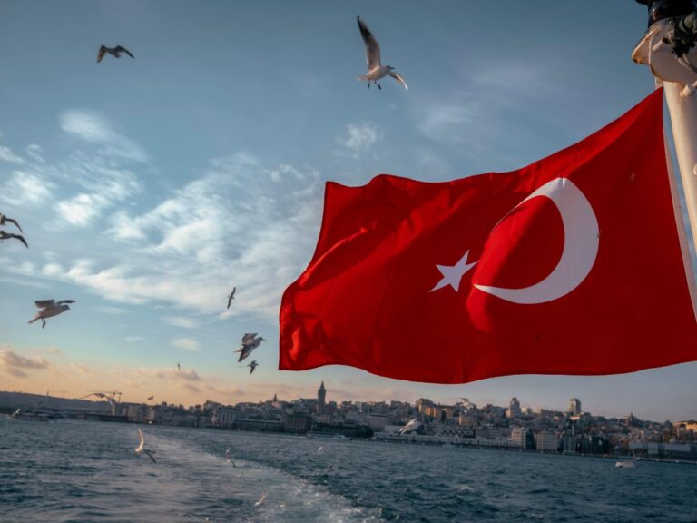 red turkish flag waving in the wind from the back of a ferry in istanbul