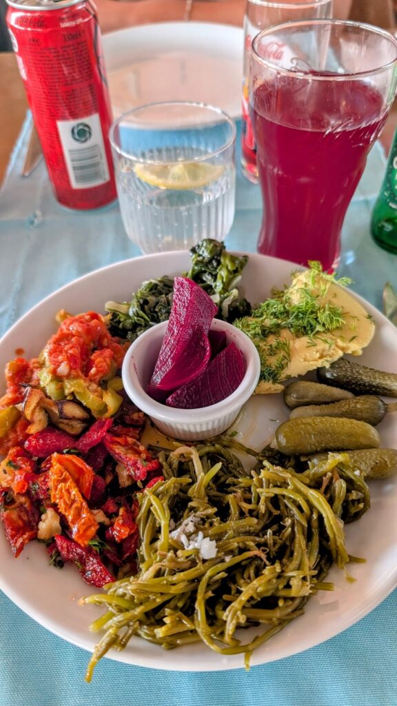 a mix of vegan mezze dishes on a small round plate next to a pink drink in turkey