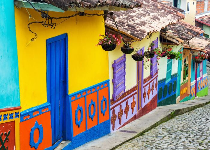 brightly colored store fronts lining a street in the small town of salento in colombia