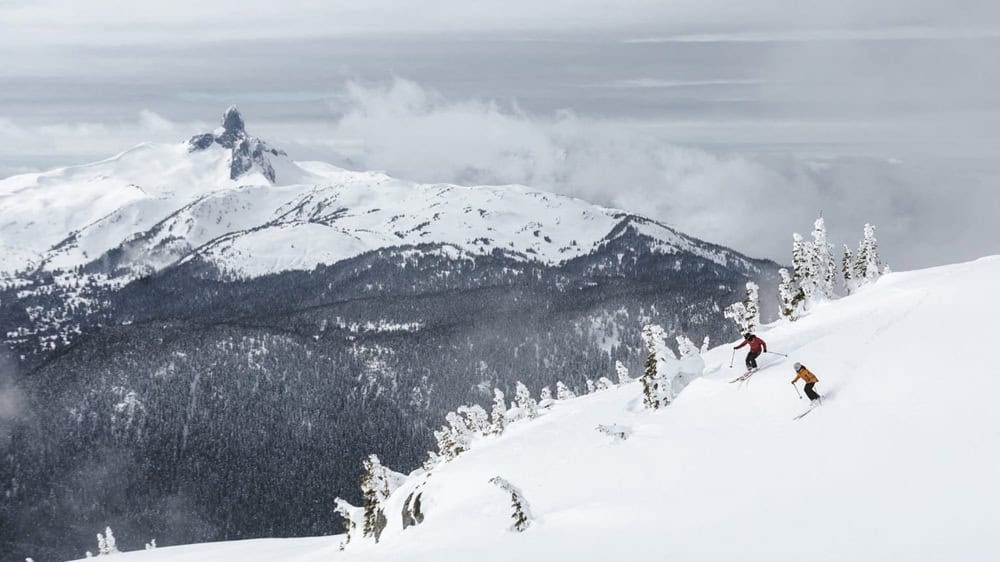 skiers heading down whistler mountain on a snowy and gray day near the four seasons resort