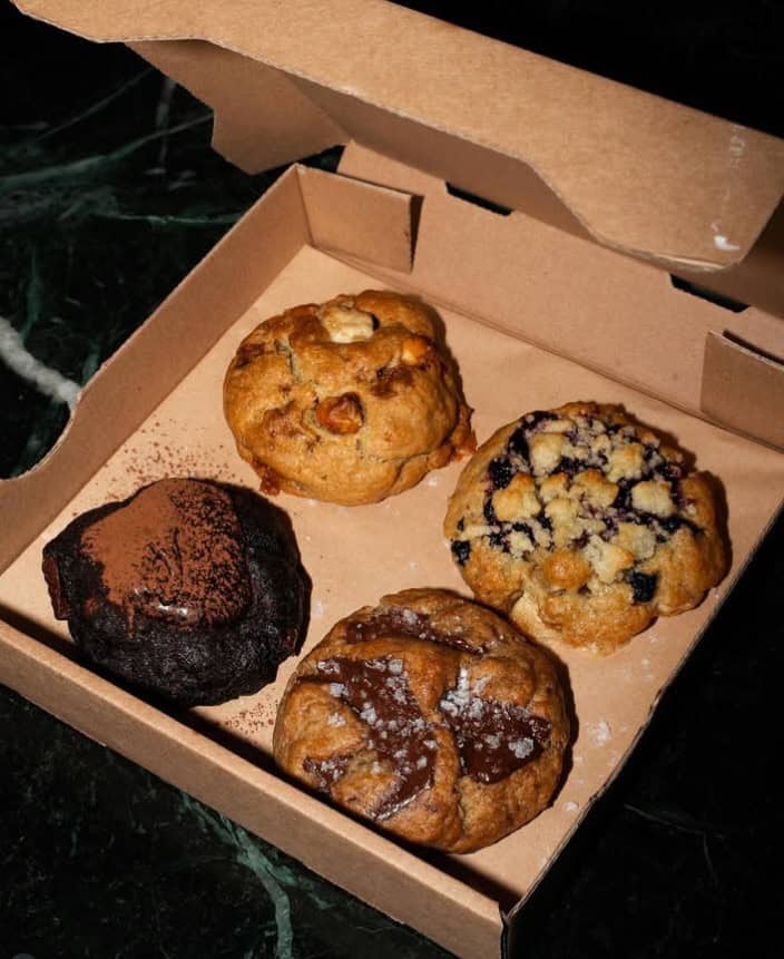 a brown cardboard pizza style box with four giant vegan cookies inside at the vegan bakery round and edgy in berlin