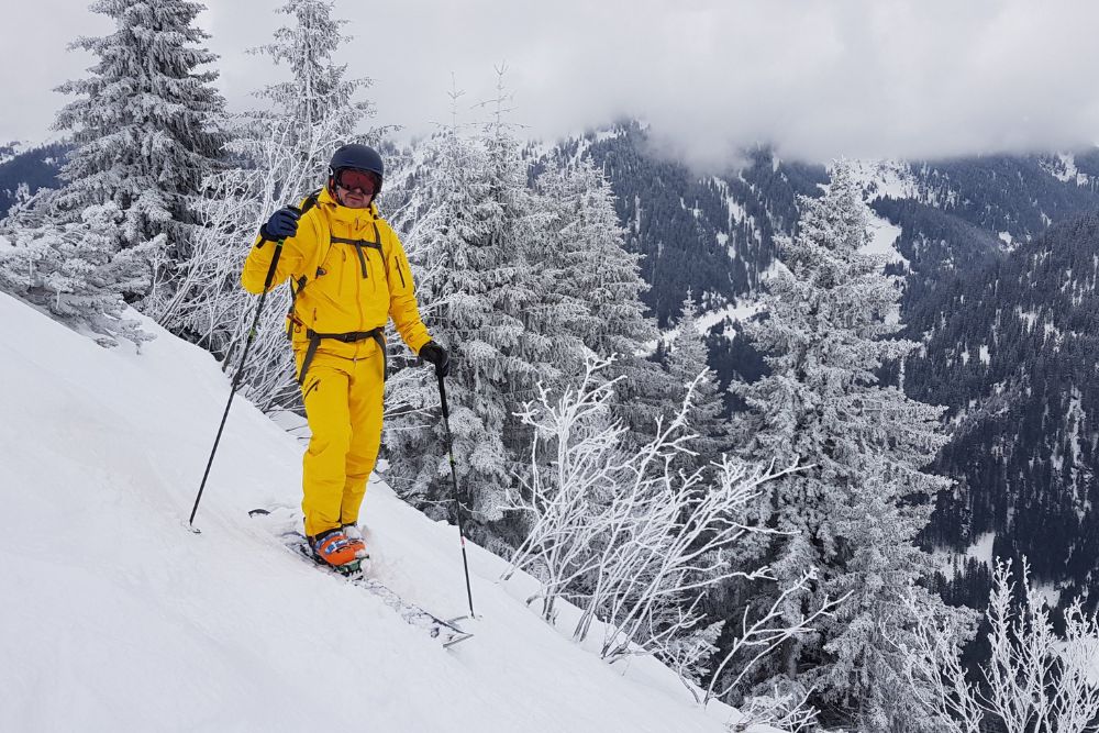 a man in a bright yellow snow suit and googles going down a snow covered mountain in austria skiing
