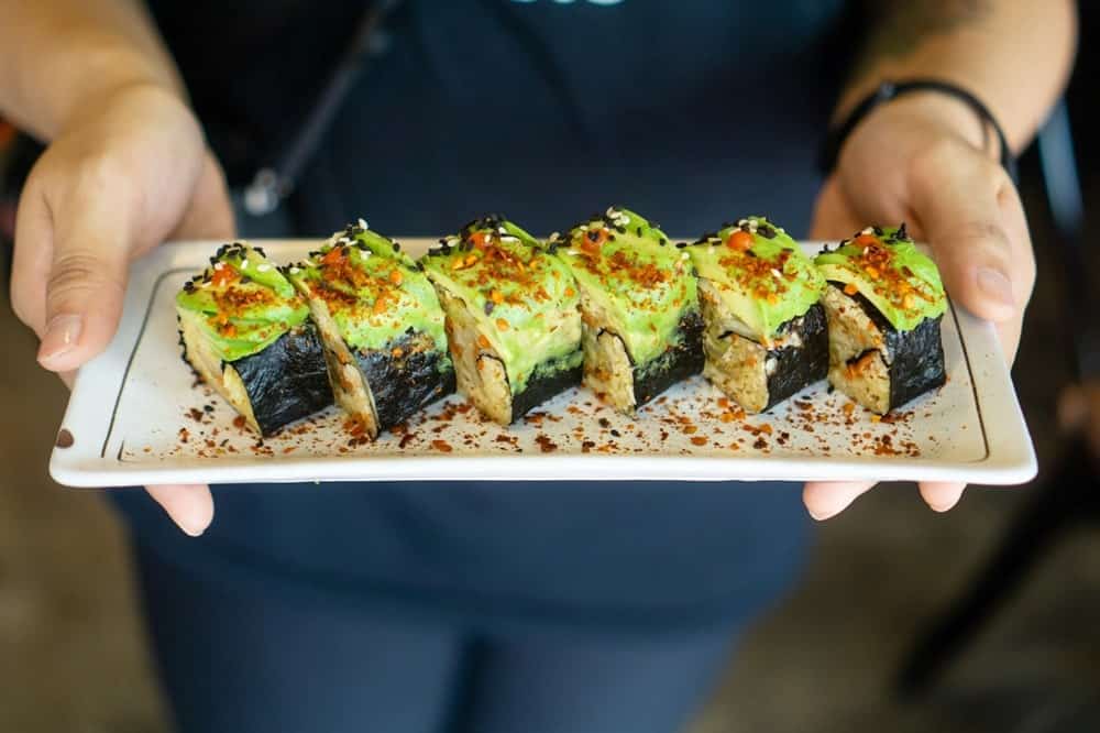 a plate of vegan sushi rolls topped with avocado on a long white plate from Afterglow by Anglow in singapore