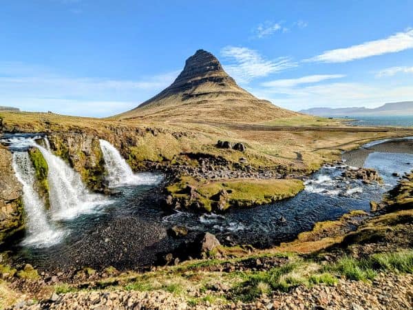 perfectly shaped mountain with three waterfalls in front of it in iceland