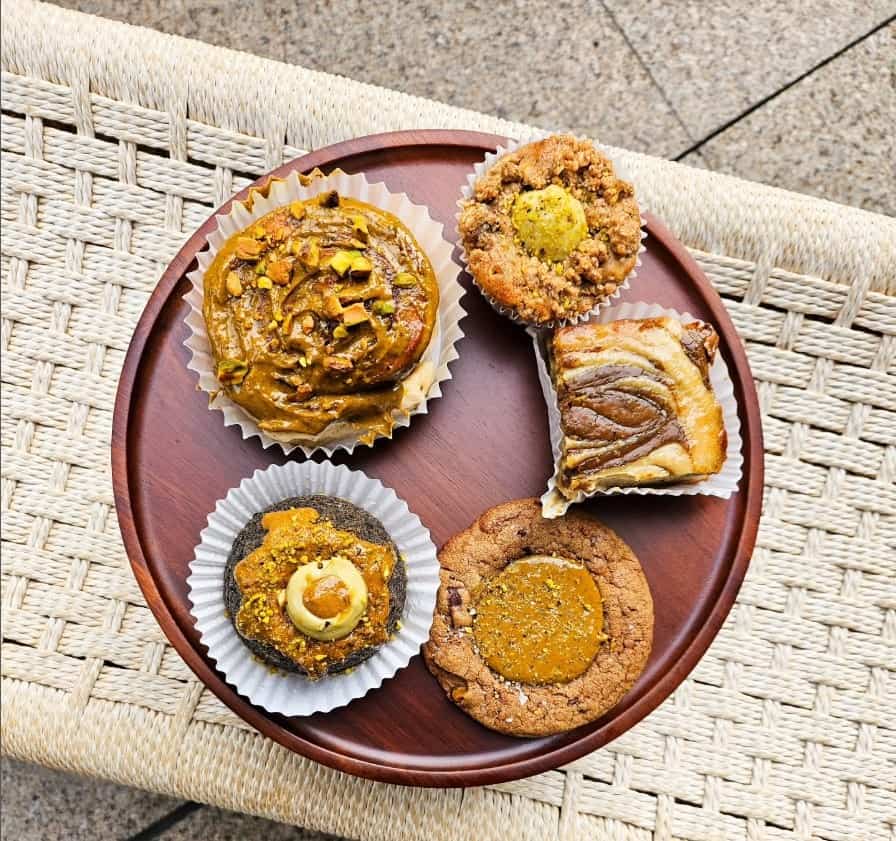 a round wooden tray with five different vegan baked goods on top from lilac oaks in singapore