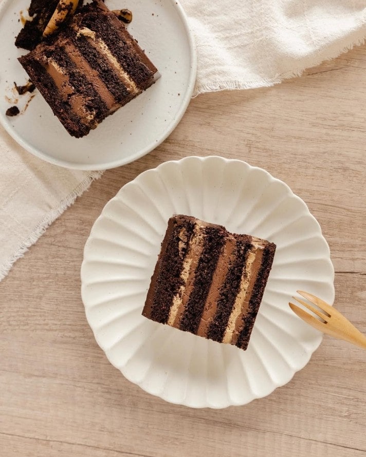 two slice of vegan chocolate cake with layers for chocolate on white plates at delicies in singapore