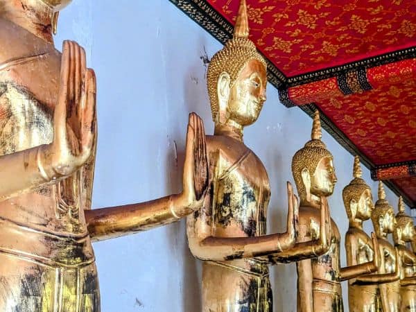 golden buddha statues standing with their palms facing out
