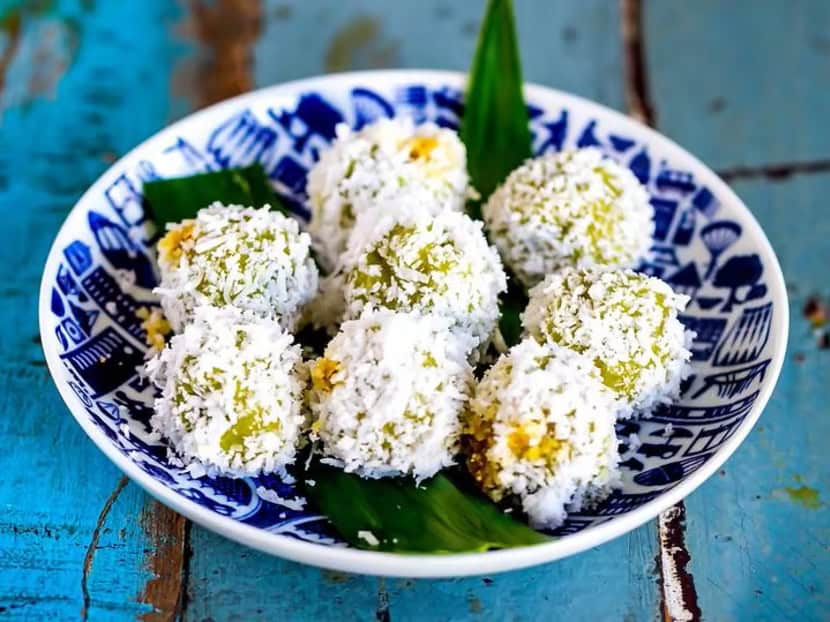 small vegan green balls that are soft, chewy and coated in grated coconut. the center is filled with warm dark palm sugar