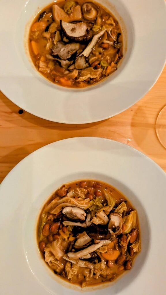 two bowls of vegan Portuguese rice and bean stew on a wood table at sete in coimbra