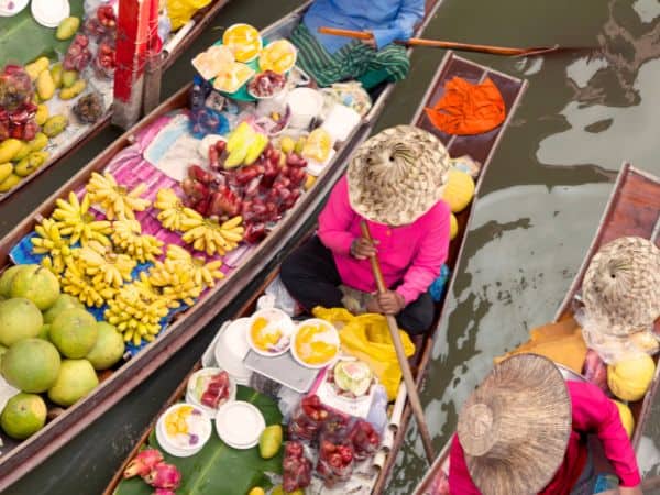 overhead shot of wooden boats carrying colorful fruit through a market in thailand