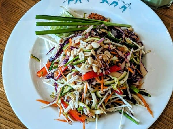 a plate of vegan pad thai with sprigs of green onion and chopped peanuts