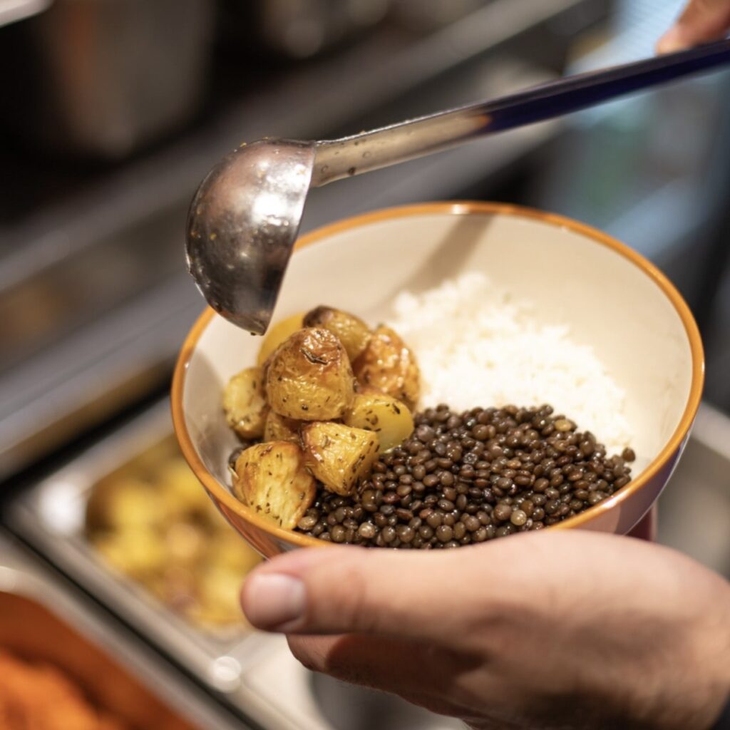 filling a small round bowl with rice and potatoes at eatsa in nice