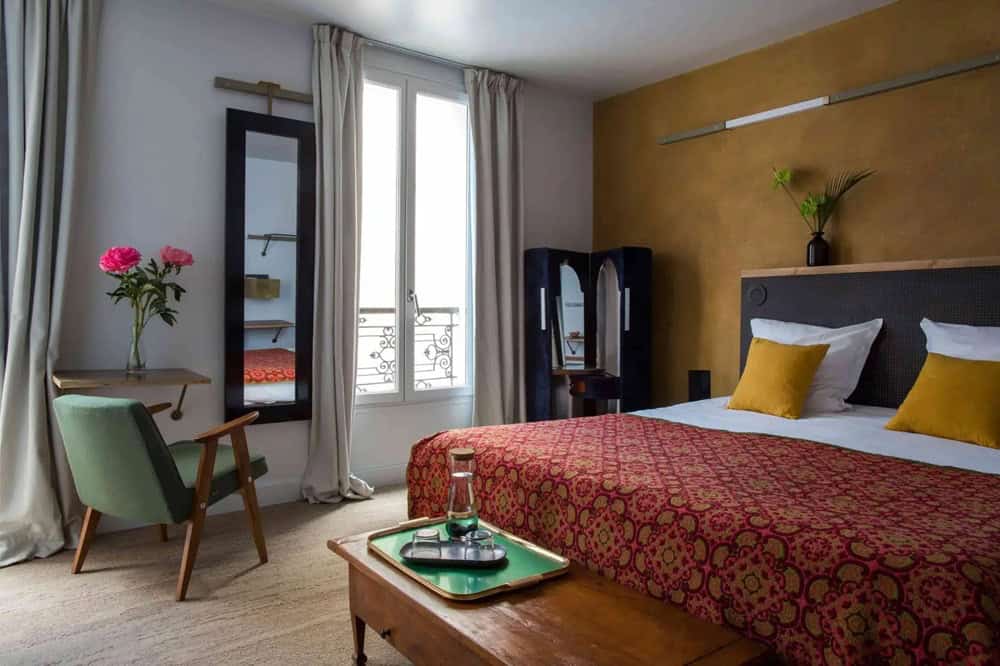 inside of a quirky guestroom with a mix of colors, fabrics and furniture at Hotel La Nouvelle République in paris