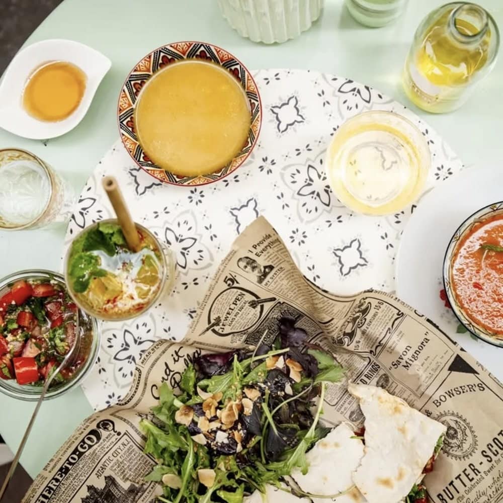 a dining table filled with a plate of mixed veggies, salad, soup, and more at saj by milla in nice