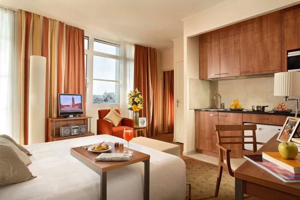 inside of a guest suite with a small kitchenette and a small table with a croissant and juice in paris
