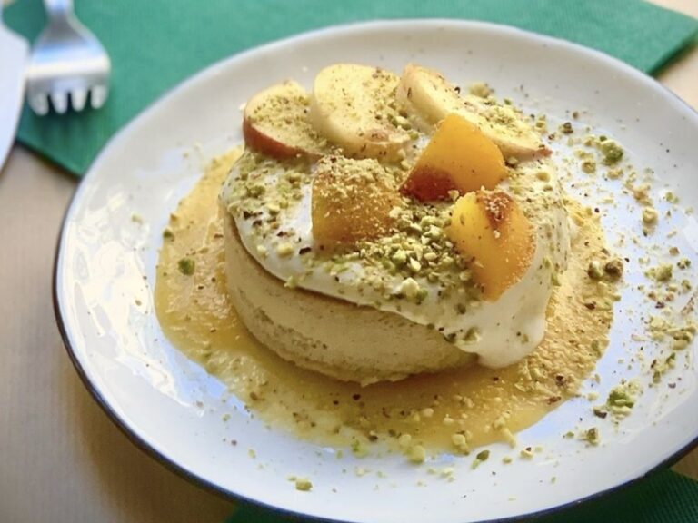 a stack of golden vegan pancakes topped with cream and sliced pears at paper plane in nice france