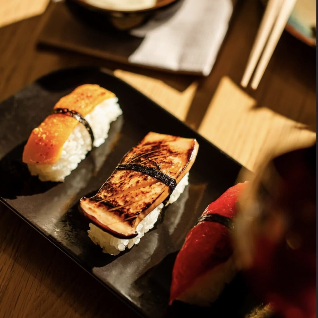 two vegan nigiri sushi rolls on a small black plate at bloom in lyon