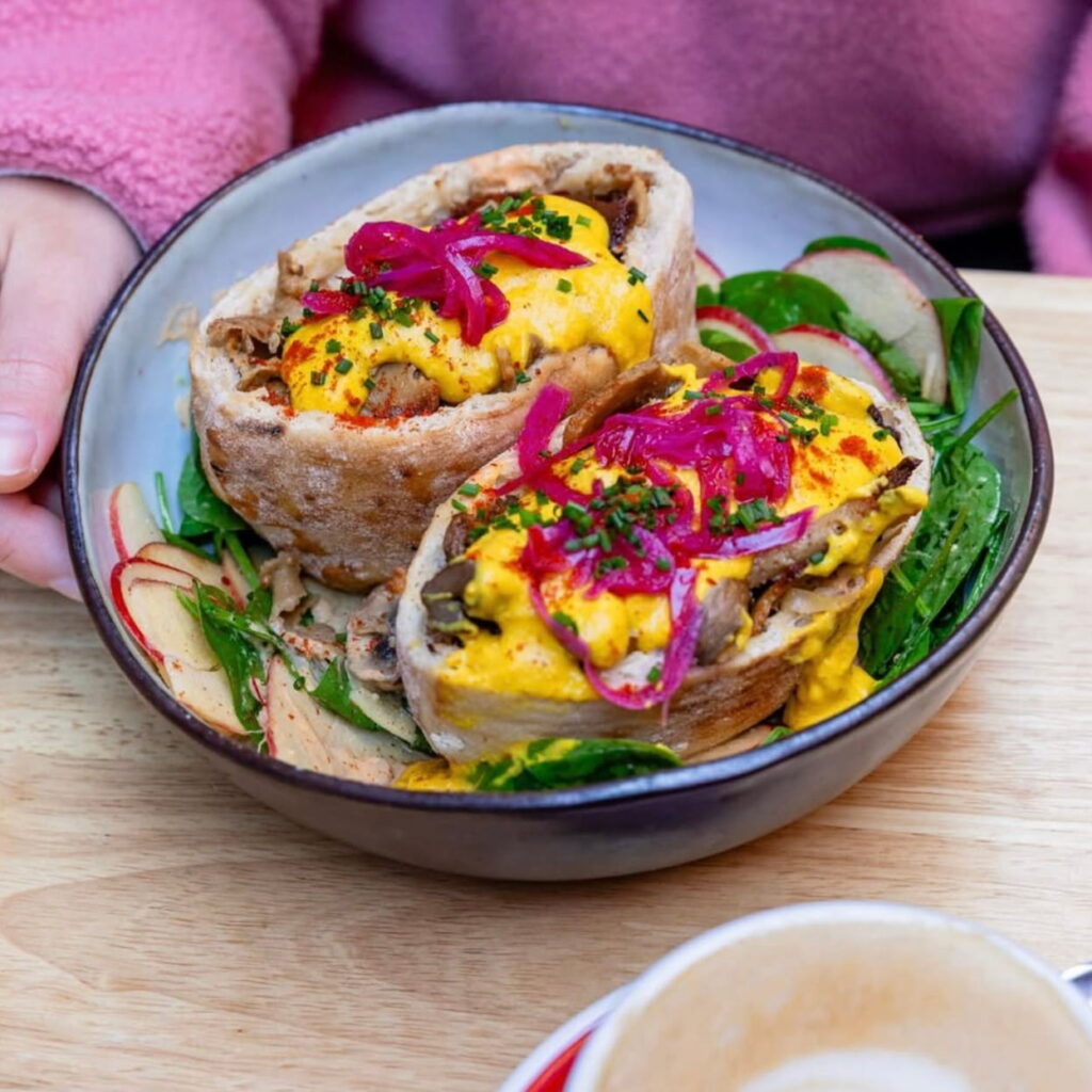 a vegan wrap cut into two filled with bright yellow tofu and bright red onions at cafe brule in toulouse france