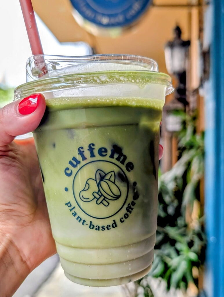 a large green vegan pandan latte with a swirl of green mixing with the white oatmilk in Phnom Penh