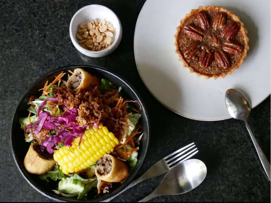colorful veggie bowl next to a mini pecan tart on a white plate at element in Phnom Penh
