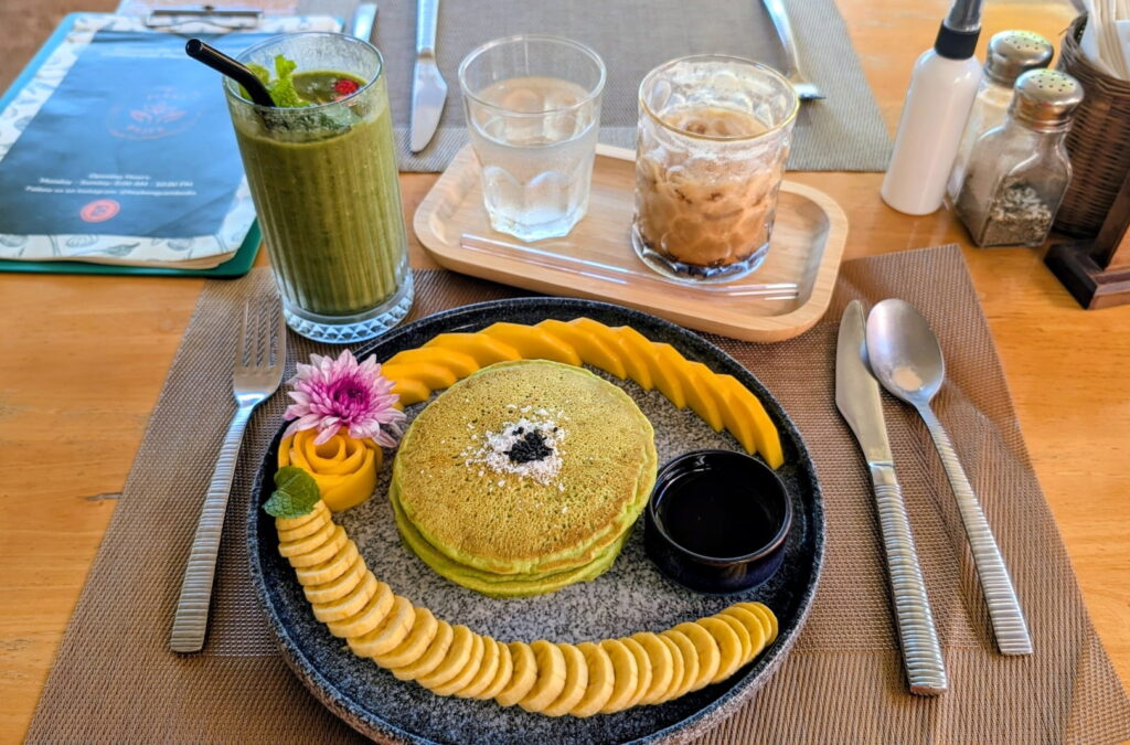 a stack of green pandan pancakes surrounded by banana slices at hey bong vegan restaurant in siem reap