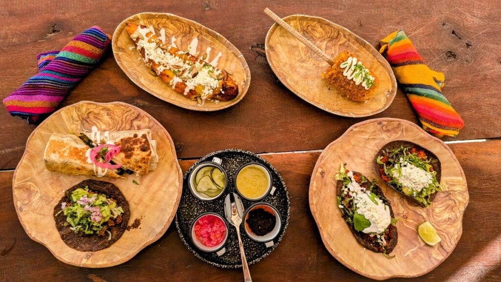 vegan burritos and tacos spread across a wood table with colorful cloth napkins in mexico