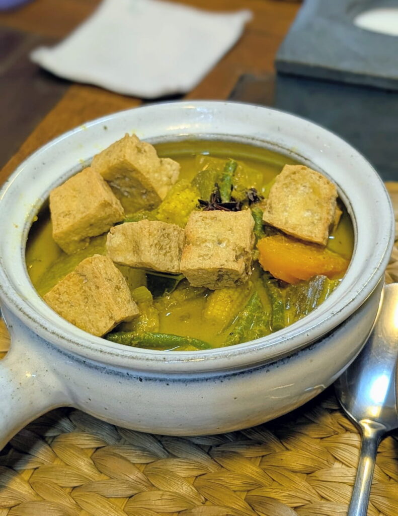 a bowl of vegan khmer curry with chunks of fried tofu at new leaf eatery in siem reap