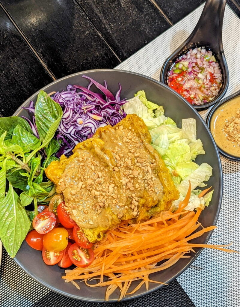 a colorful vegan veggie bowl with a mix of fresh vegetables under tempeh coated in a peanut sauce at the planters in krabi