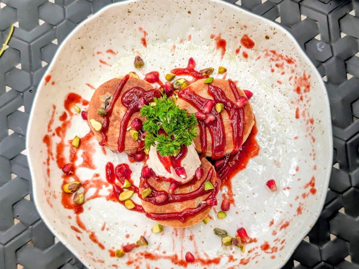 a stack of three mini golden pancakes topped with raspberry syrup at the quarter in Koh Phangan