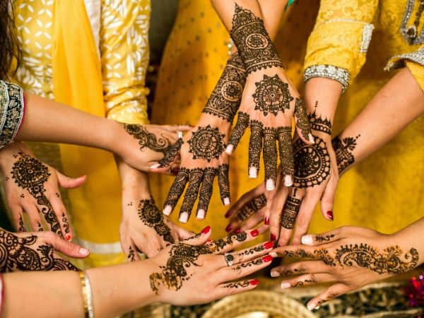 women in bright yellow dresses with their hands covered in henna
