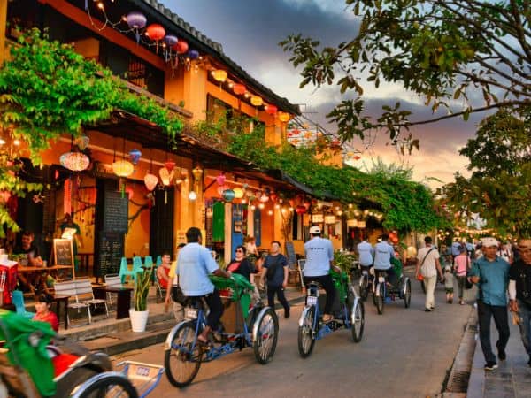 a group of people biking through hoi an at night